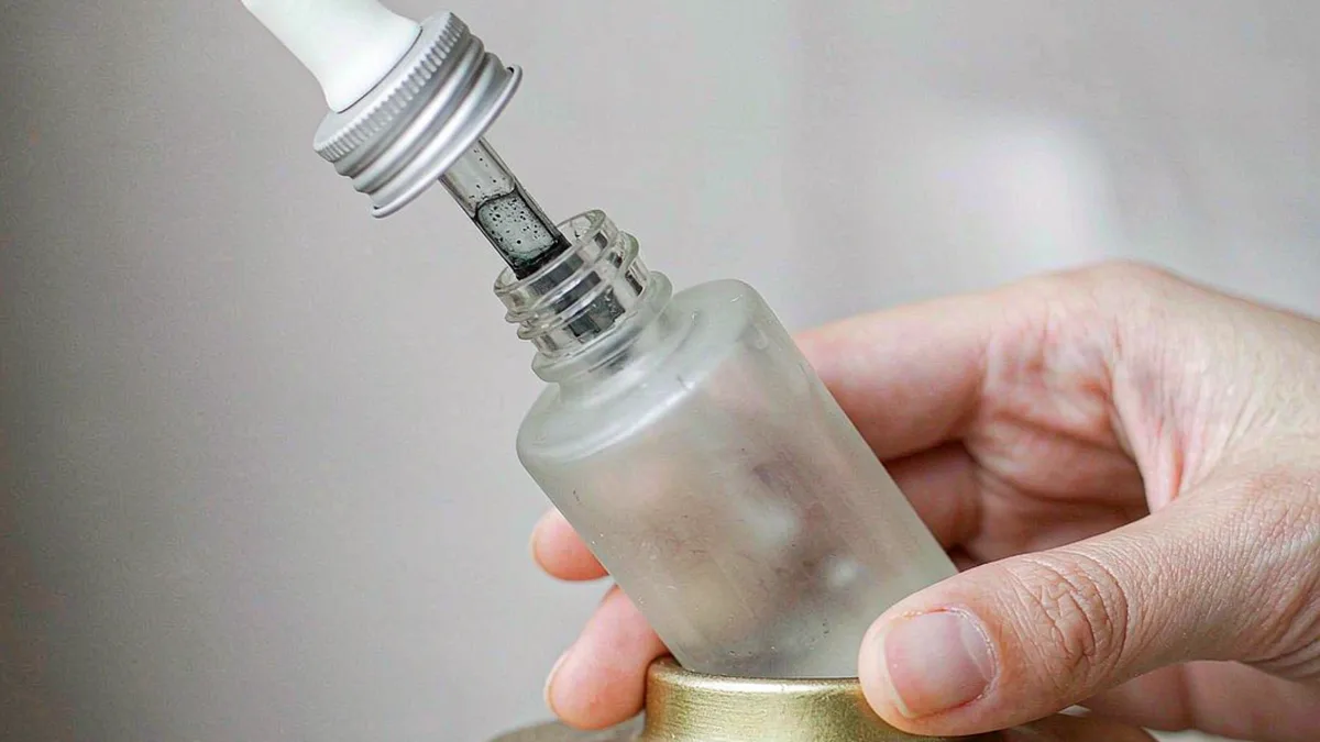 Close-up of a push-and-turn child-resistant cap on a frosted glass dropper bottle for skincare serum