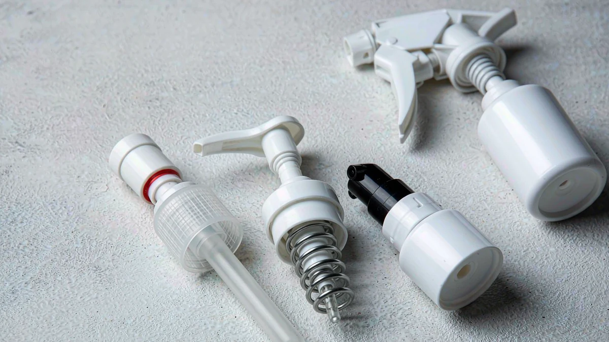 Flat lay of cosmetic dispensing closures grouped by neck finish: dropper, lotion pump, fine-mist sprayer and trigger sprayer on a neutral studio background