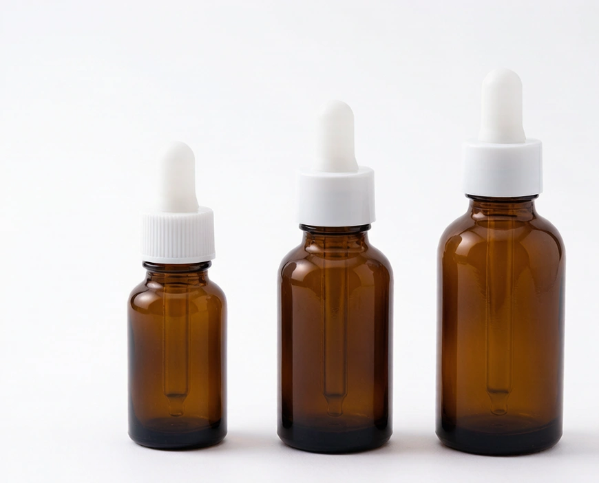 Three amber glass dropper bottles with platinum-cured silicone bulbs on white background