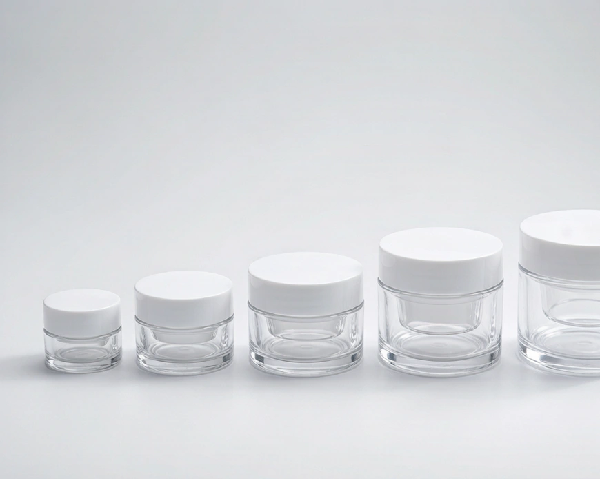 Double-wall plastic cream jars in several sizes on a light neutral background