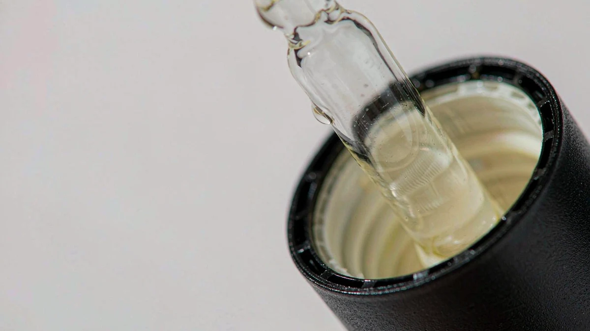 Macro close-up of a glass dropper bottle neck and cap interface showing the threaded closure and rubber bulb