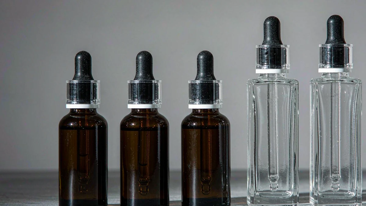 A row of amber and clear glass cosmetic dropper bottles sealed and standing upright on a clean studio background
