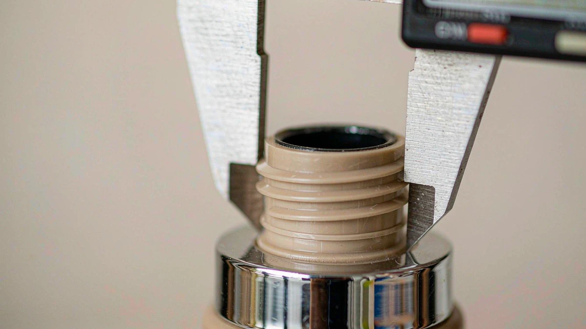 Close-up of a cosmetic bottle neck finish and cap thread being measured with calipers during sample inspection
