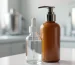 Opaque amber airless pump bottle standing beside a clear glass dropper bottle on a clean minimalist beauty lab bench